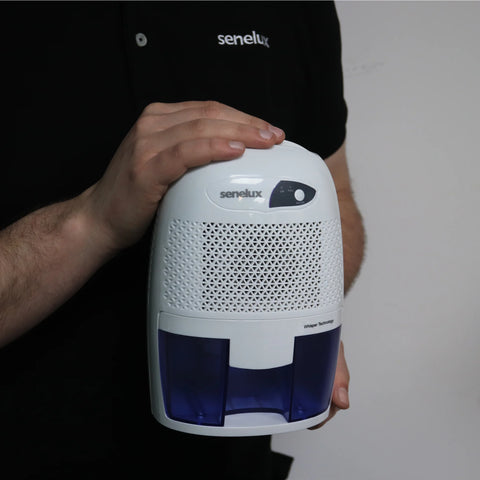 A picture that shows a Senelux engineer wearing a Senelux polo shirt holding up a Senelux Mini Dehumidifier