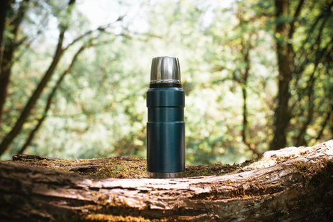 vacuum insulated bottle on wooden log in the woods