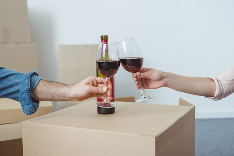 man and woman clinking wine glasses on top of a box