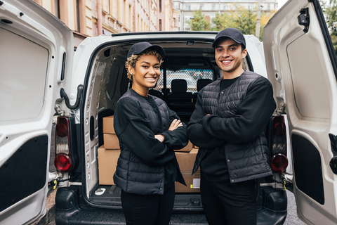 happy man and woman standing outside delivery van