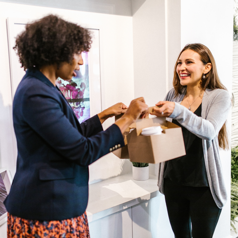 Corporate Gifts and Hampers can make staff feel cared for - woman giving gift to coworker