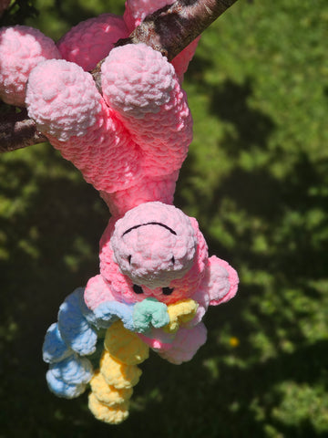 Stuffed handmade unicorn plushy hanging upside down in a tree