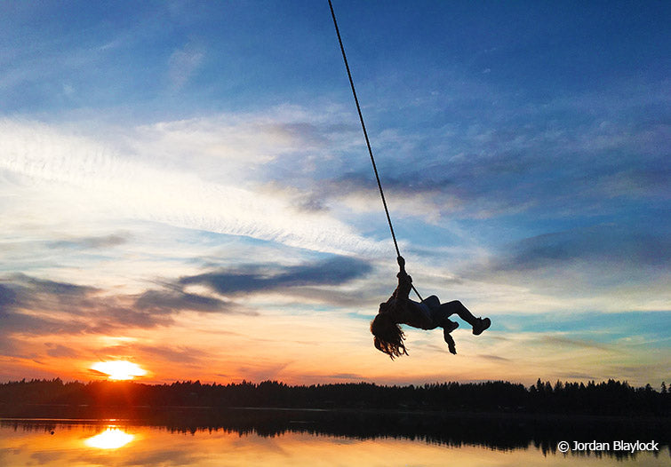 Child on waterfront rope swing