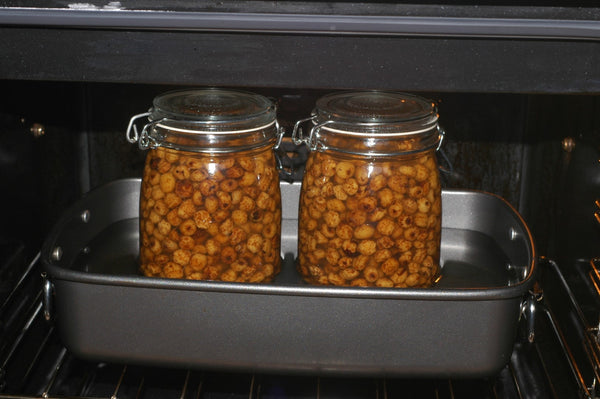 Photo of two mason jars full of round bait in a baking tray in oven