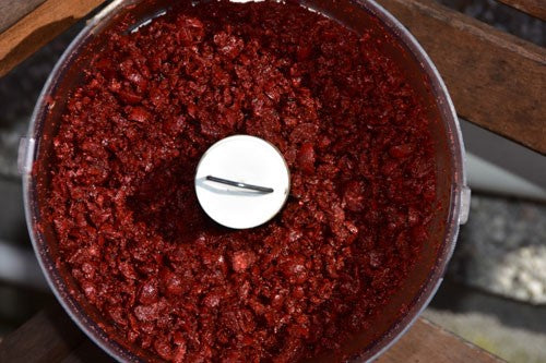 Glossy, red blended pellets in a food processor.