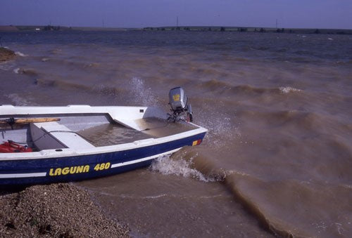A boat on the sandy shore, next to a choppy sea.