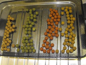 Round, coloured boilies lined up in a silver tray.