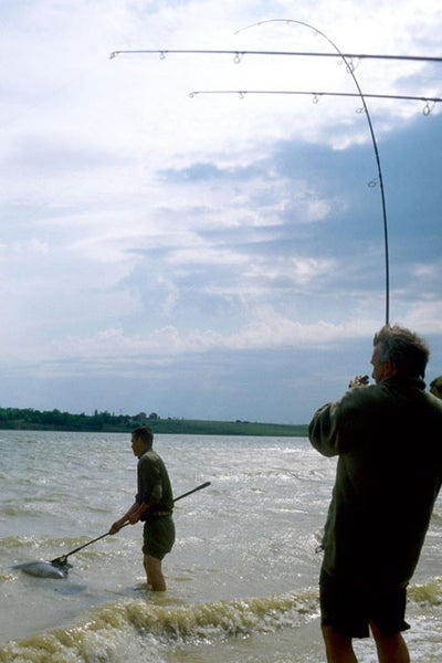 Two men fishing near choppy water.