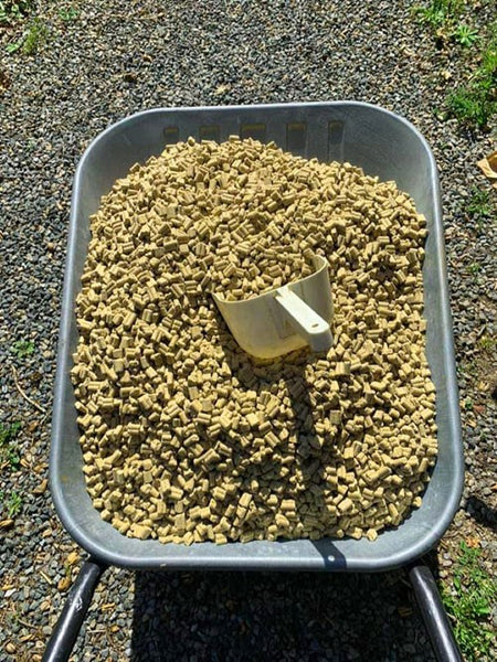 Wheelbarrow filled with brown, cereal-based fishing pellets.