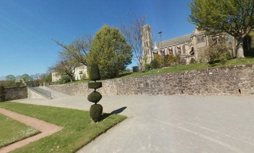 Large stone church behind a cobbled wall.