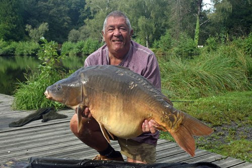 Ken kneeling with a huge carp in his hands.