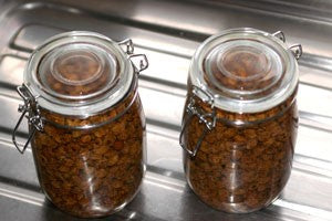 Two jam jars filled with tiger nuts and boiling water, with their lids closed.