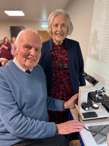 Professor John E Cooper and his wife Margaret next to a microscope.