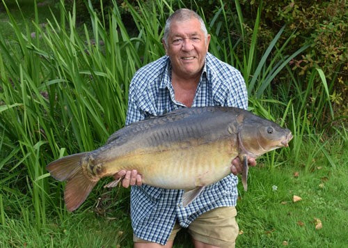 Ken smiling whilst holding a large carp fish.