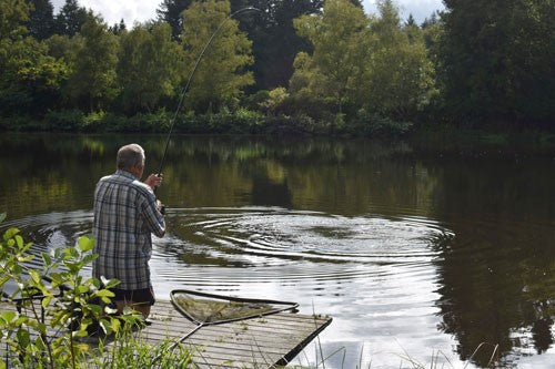 Ken fishing on a still lake, with a long fishing line.