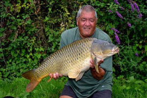 Ken kneeling and holding a big carp.