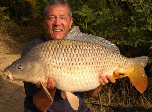 Ken smiling whilst holding a large scaled fish.