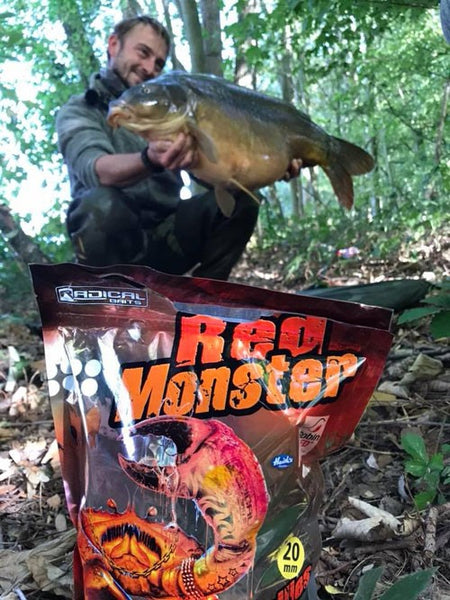 Man behind Red Monster packaging, holding a large fish.