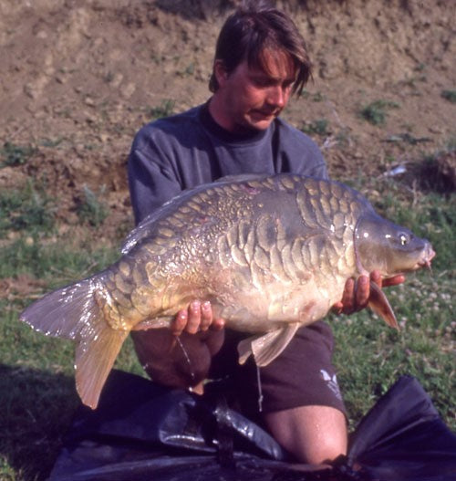 A man kneeling and holding a large fish.