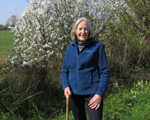 Margaret Cooper in front of a blooming tree and greenery.