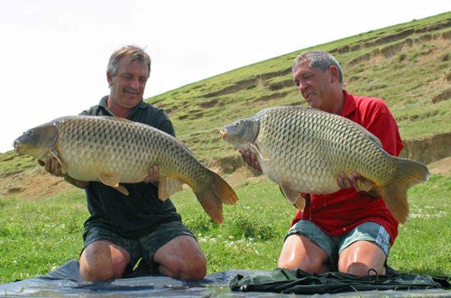 Phil and Ken kneeling down and holding their carp catches.