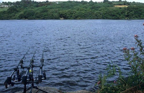 Photo of a lake with three fishing rods stretching out into the water