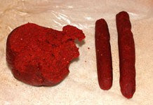 Image of red bird food base mix being cut into sausage shapes