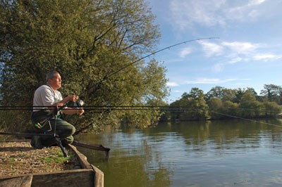 Image of Ken Townley sat on the lakeside on his peg with his rods in the lake
