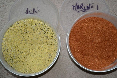 Photograph of two pots of bait. One yellow powder with black seeds in and one with orange bait