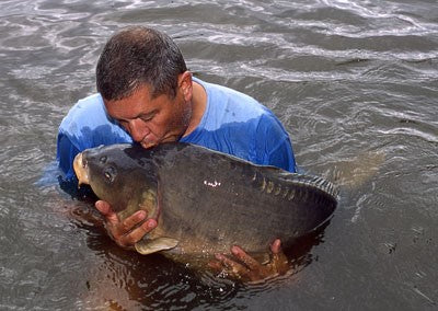 Image of Ken Townely kissing a large carp while stood in the lake