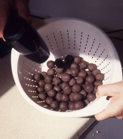 Photograph of a bowl of red round fishing boilies being dried with a hairdryer