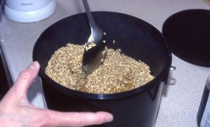 Image of a black bucket with boiled bait in it being stirred with a metal spoon