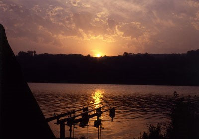 Image of a lake at dusk with fishing rods on the bank