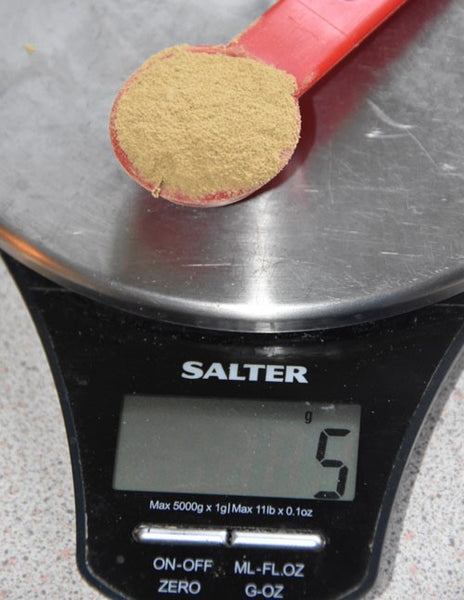 Photo of red measuring spoon containing liver extract powder on a scale