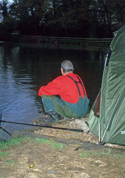 Photo of Ken Townley sat at dusk on the banks of a fishing pond