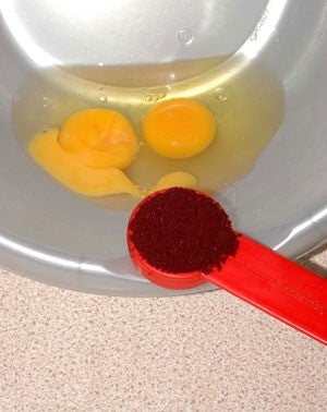 Red measuring spoon with Robin Red in front of egg yolk and white.