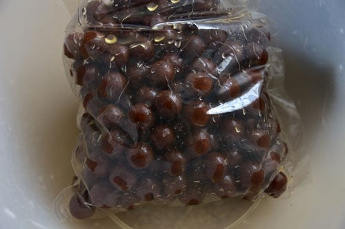 Sealed bag of dark brown fishing boilies.