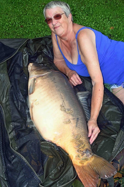 Tat laying next to a large, almost fifty-two pound carp.