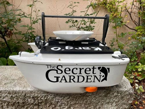 Bait boat with black writing across the side, 'The Secret Garden.'