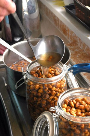 Someone ladling boiling tiger nut water into jam jars.