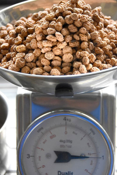 One kilo of tiger nuts on a silver scale.