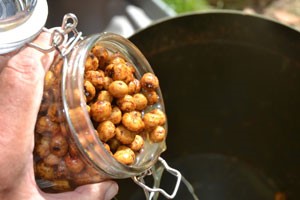 A hand pouring tiger nuts out of a glass jam jar.