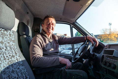 A man truck driver is sitting in the cab of a modern truck.