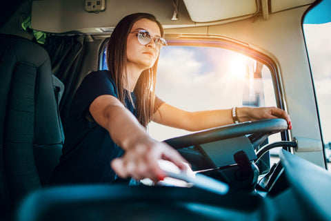 Portrait of beautiful young woman professional truck driver sitting and driving big truck.