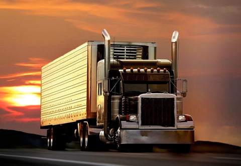 Big truck driving on a highway with sunset in background