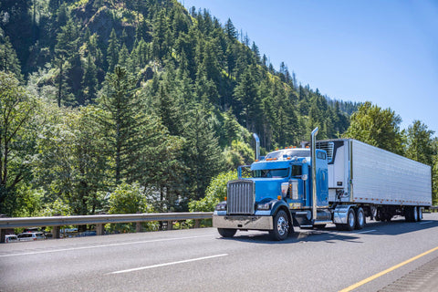 Blue big rig long haul semi truck running on the highway road