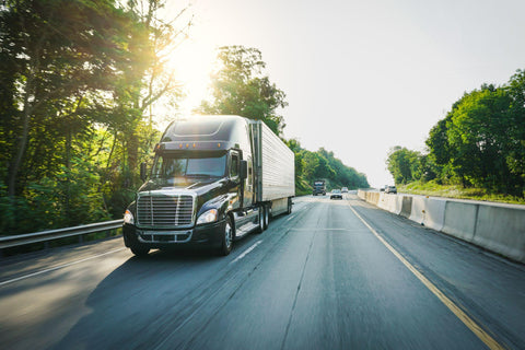 Dark semi truck on highway in daylight 