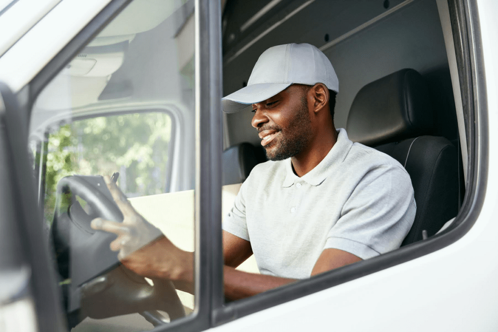 delivery man reading from device while sitting in delivery van