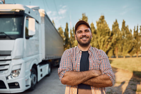 Happy professional driver with crossed arms standing on parking lot