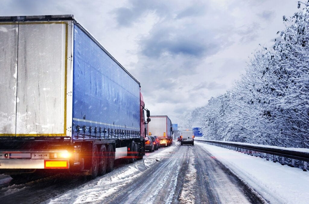 Onset of winter snowy truck in traffic jam on highway